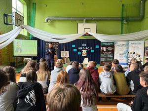 Policjantka stoi przed grupą siedzących dzieci.