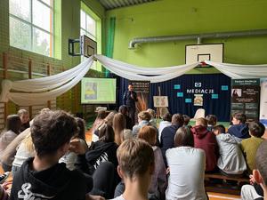 Policjantka stoi przed grupą siedzących dzieci.