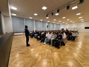 Policjantka na sali gimnastycznej stoi przed uczniami.