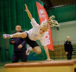 Dziewczynka przeskakuje przez kozła.