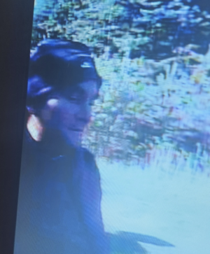 Twarz mężczyzny w ciemnej czapce z jasnym napisem.