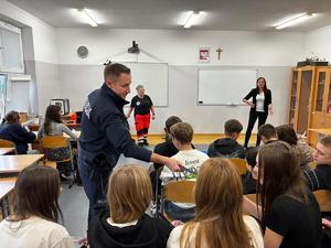 Policjant rozdaje odblaski uczniom.