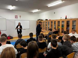 Policjant rozdaje odblaski uczniom.