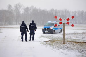 Dwóch Policjantów sprawdzają torowisko, w tle znajduje się radiowóz.