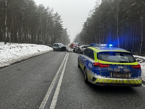 Radiowóz i dwa pojazdy w tle po zdarzeniu drogowym.