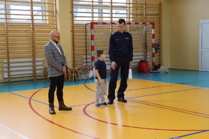 Komendant wraz z wójtem stoją z dzieckiem.