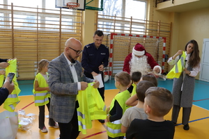Komendant wraz z wójtem rozdają dzieciom odblaski.
