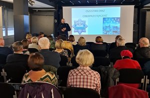 Policjant stoi przed seniorami.