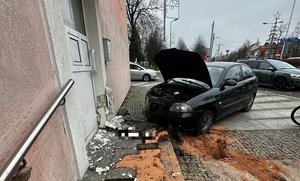 Rozbity samochód przy uszkodzonym budynku.