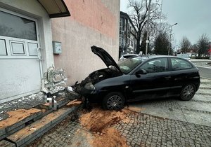 Rozbity samochód przy uszkodzonym budynku.