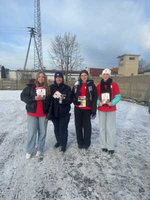 Policjantka stoi z wolontariuszami.