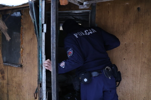 Policjant zaglądający do pustostanu.