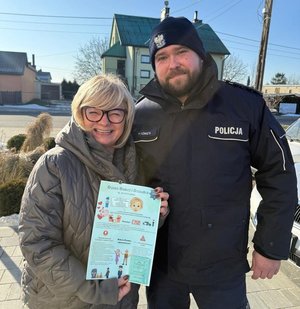 Policjant z seniorką, która trzyma w ręku ulotkę.