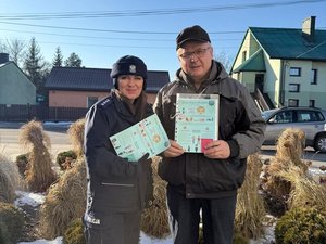 Policjantka z seniorem, który trzyma w ręku ulotkę.