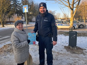 Policjant z seniorką, która trzyma w ręku ulotkę.