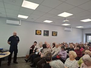 Policjant stoi przed grupą ludzi.