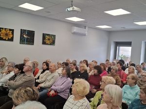 Grupa ludzi siedzi na krzesłach.