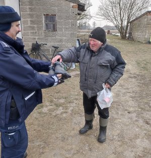Policjant przekazuje buty mężczyźnie.