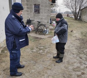 Policjant stoi na przeciwko mężczyzny na podwórku.