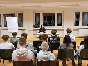 Kobieta siedzi przed młodzieżą.