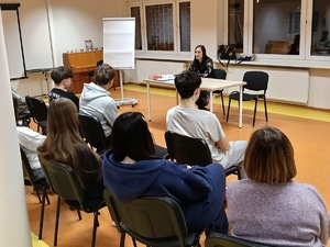 Kobieta siedzi przed młodzieżą.