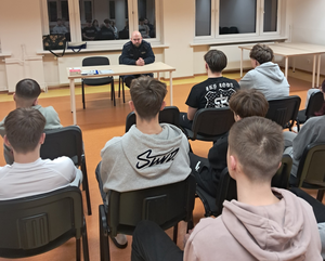 Policjant siedzi przed młodzieżą.