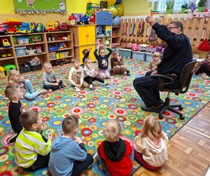 Policjant siedzi przed grupą dzieci.