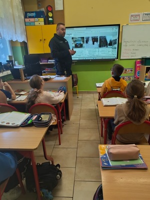 Policjant stoi przed dziećmi.