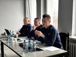 Trzech komendantów siedzą za biurkiem.