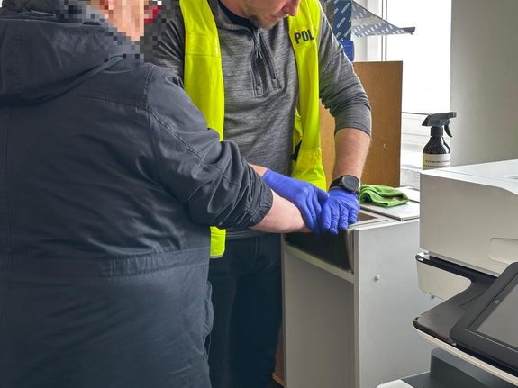 Policjant zbiera odciski palców od kobiety.