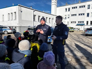 Policjant pokazuje krótkofalówkę dzieciom.