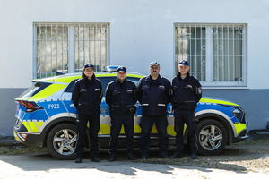 4 dzielnicowych na tle radiowozu.