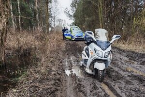 Motocykl, który ugrzązł w błocie w tle radiowóz.