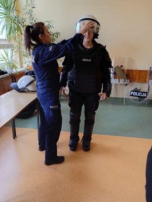 Policjantka zakłada kask na głowę uczniowi ubranemu w tzw. "żółwia".