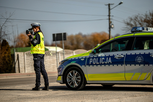 Policjantka mierzy prędkość przy radiowozie.