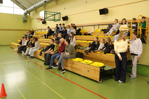 Uczestnicy i opiekunowie siedzą na trybunach.