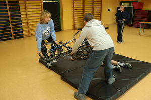 Dzieci zdejmują rower z poszkodowanego.