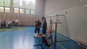Policjanci przed uczniami na sali gimnastycznej.