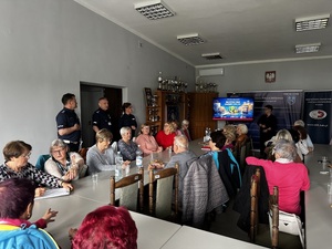 Policjanci witają seniorów w auli Komendy Powiatowej Policji w Bełchatowie.