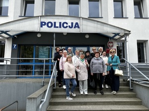 Seniorzy stoją do zdjęcia przed Komendą Powiatową Policji w Bełchatowie.