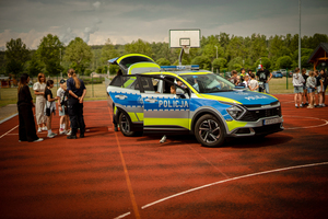 Policjantka z dziećmi przy radiowozie.
