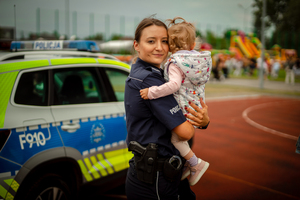 Policjantka trzyma dziecko na ręku.