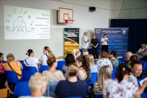 Policjantka wita gości w hali sportowej.