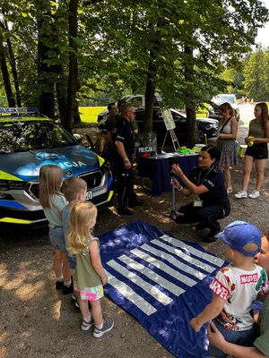 Policjantka uczy dzieci poprawnego przechodzenia przez jezdnię.