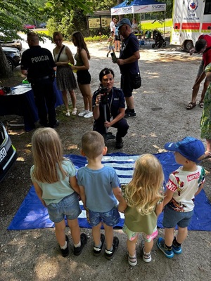 Policjantka uczy dzieci poprawnego zachowania na przejściu dla pieszych.