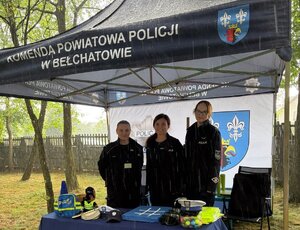 Trzy policjantki stoją na stoisku profilaktycznym.