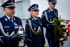 Oficerowie składają kwiaty i znicz przed tablicą pamiątkową.