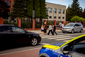 Policjanci dbają o bezpieczeństwo przy przejściu dla pieszych obok szkoły.