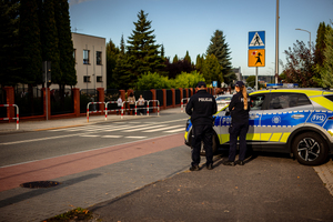 Policjanci dbają o bezpieczeństwo przy przejściu dla pieszych obok szkoły.