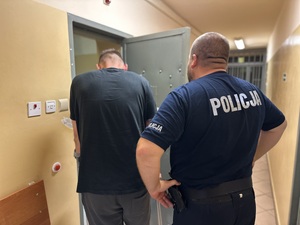 Policjant tyłem z zatrzymanym.